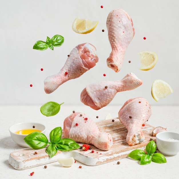 Premium Photo | Raw Chicken Drumstick And Spices Fly Over The Cutting ...